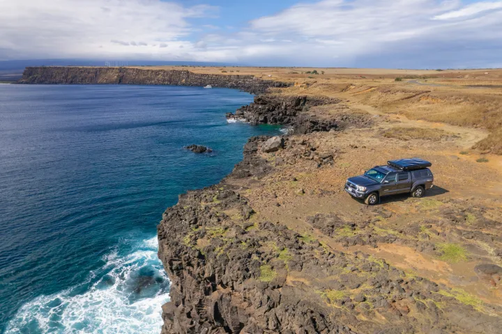Adventure-ready RV rental truck perched on a rugged cliff overlooking the blue ocean. Ideal for exploring scenic coastal landscapes.. Other Other 2013