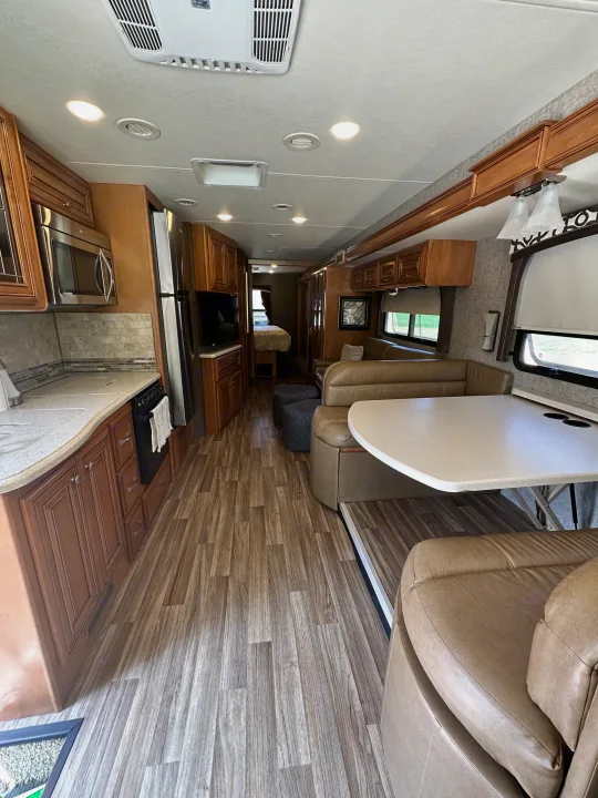 Spacious rv rental interior showcasing a full kitchen, comfortable living/dining area, and a view of the rear bedroom.. Thor Miramar 2017