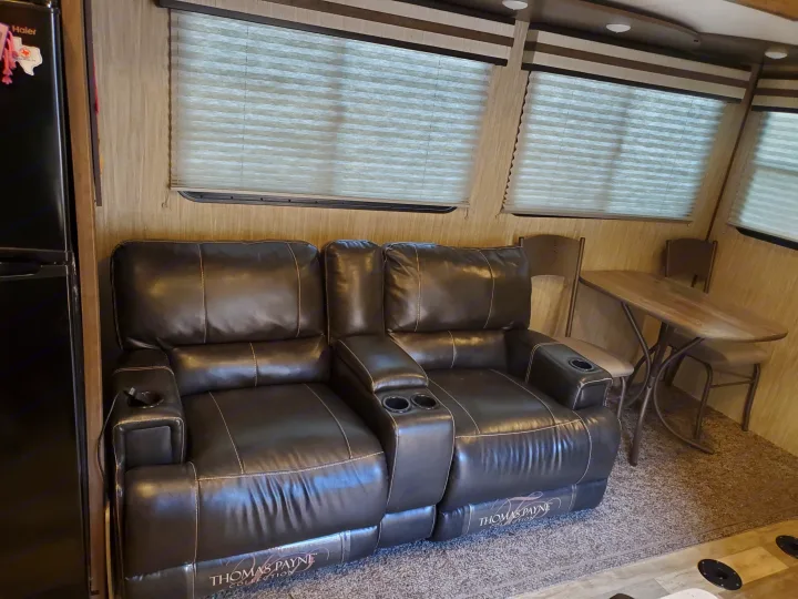 RV rental interior: cozy dark leather recliners with cup holders, alongside a dining table with two chairs under windows.. Other Other 2019