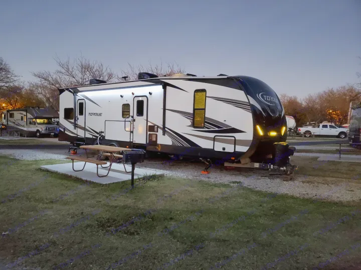 Illuminated RV rental at a peaceful campground at dusk, with a picnic table and grill ready for use.. Other Other 2019