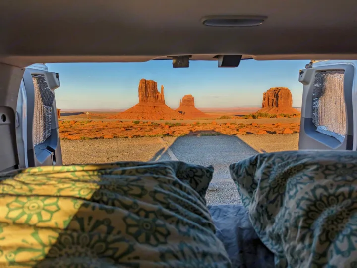 RV rental: Iconic Monument Valley red rock formations glow in golden light, viewed from inside a vehicle's bed.. Ford Transit 2016