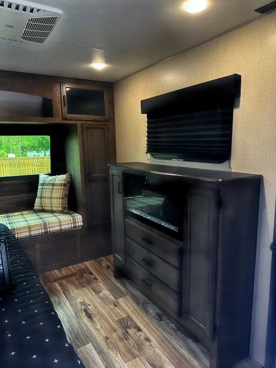 Cozy RV rental interior featuring built-in bench seating, electric fireplace, and modern wood-toned cabinetry.. Sport Trek Touring 2021