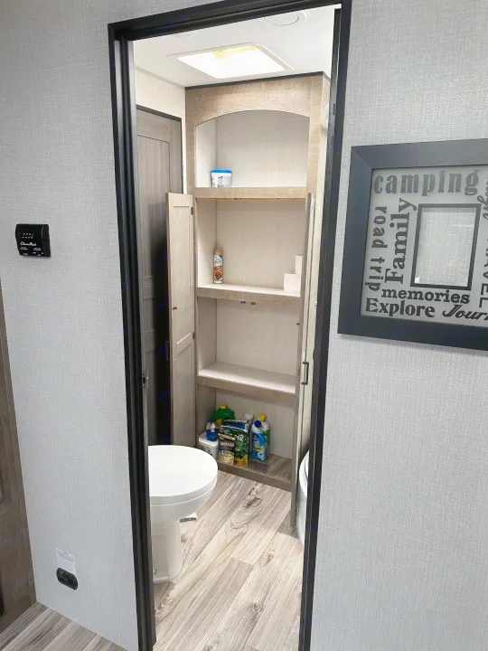 Explore your RV rental's smart storage: A compact bathroom with toilet, shelves, and supplies for easy road trips.. Sport Trek Touring 2021
