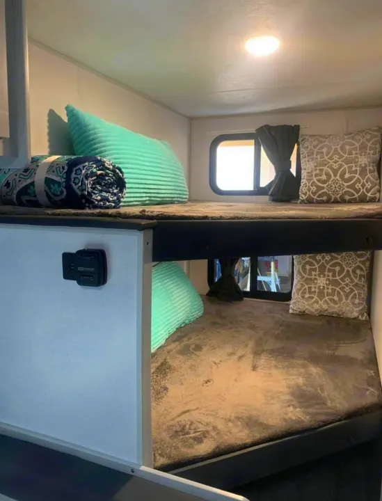 Experience comfort in this cozy RV rental! Bunk beds with soft bedding and pillows, plus windows, offer a perfect resting space.. Forest River Salem FSX PLATINUM 2021