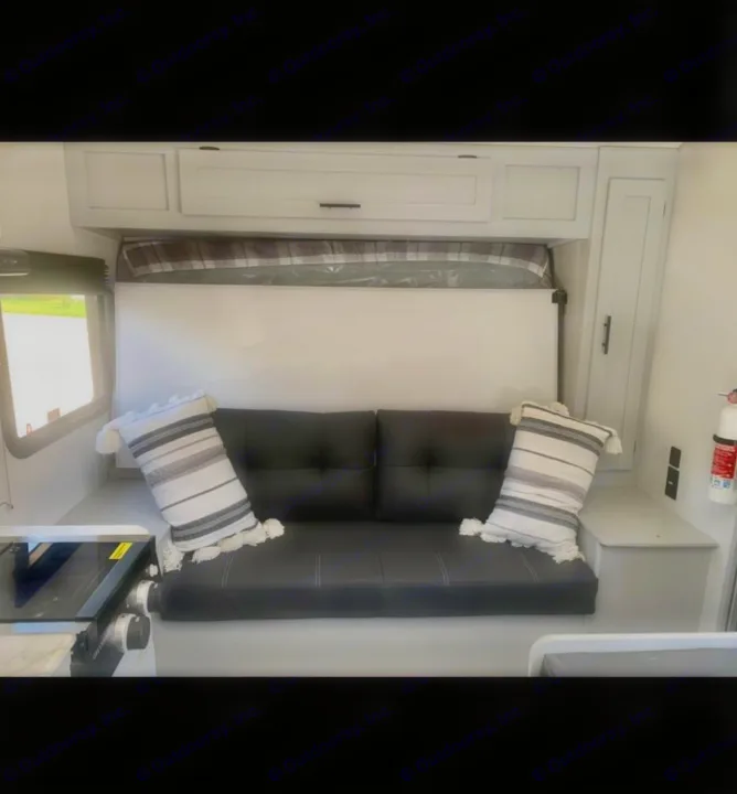 RV rental interior: a black sofa converts to a bed under white cabinets. Features a compact kitchen & window.. Forest River Salem FSX PLATINUM 2021