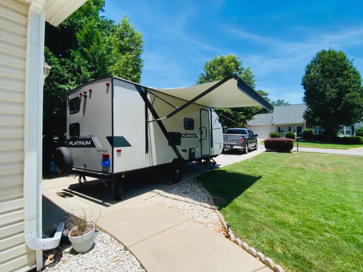 Light gray travel trailer with extended awning & truck parked in sunny driveway. Great for an rv rental trip.. Forest River Salem FSX 2020