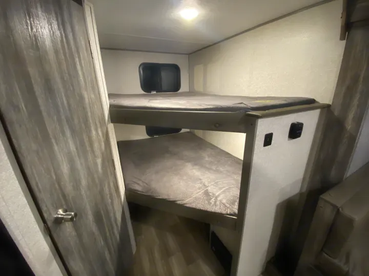 RV rental: Interior view of compact bunk beds with grey mattresses and a small window, perfect for extra sleepers.. Forest River Salem FSX 2020