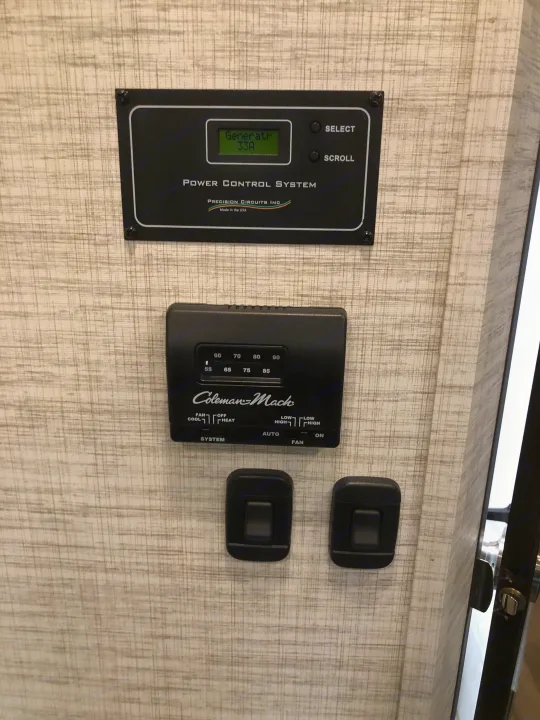 RV rental interior: power control system displaying generator output and a Coleman-Mach thermostat with fan and temperature controls.. Jayco Redhawk 2024