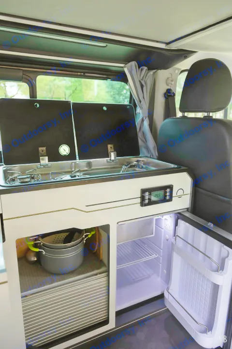 Explore an RV rental's efficient campervan kitchen. It features a compact stovetop, sink, open fridge, and accessible storage.. HANROAD TREK 4 2024