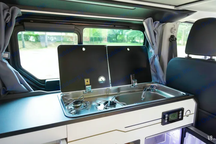 Modern RV rental interior: compact kitchen with two-burner stove, sink, and fridge. Perfect for road trips.. HANROAD TREK 4 2024