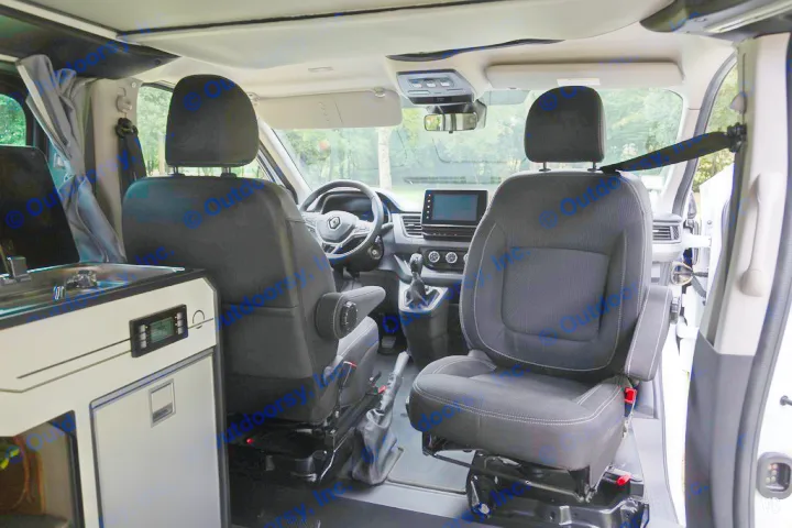 Interior of a compact RV rental featuring front swivel seats, a dashboard, and a built-in kitchenette with a fridge.. HANROAD TREK 4 2024