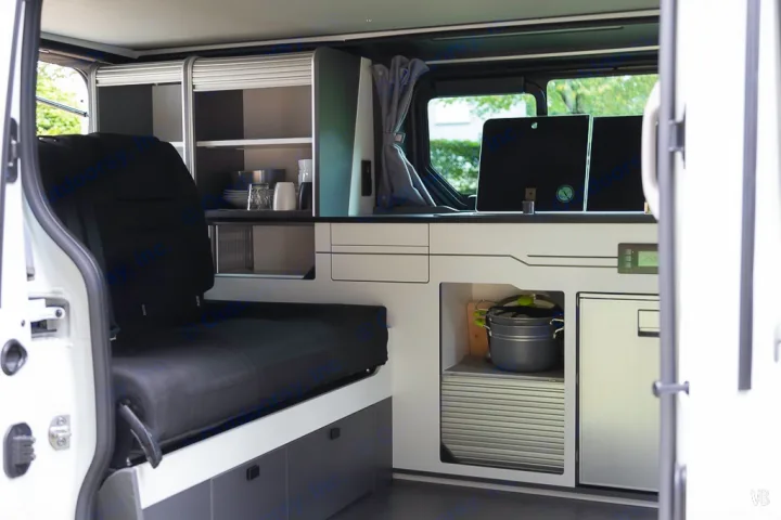 Inside a modern RV rental: compact kitchenette, smart storage, and seating make this campervan ideal for travel adventures.. HANROAD TREK 4 2024