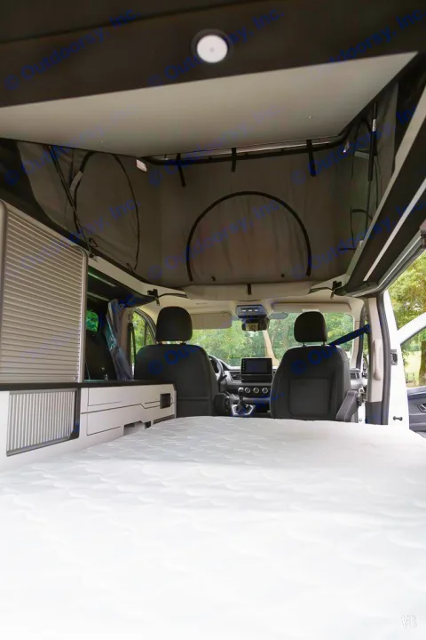 Spacious RV rental campervan interior with a pop-top roof, bed, and view of the front cabin seats.. HANROAD TREK 4 2024