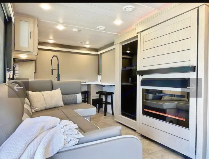 Cozy RV rental living area featuring a modern kitchen, comfortable sectional, and electric fireplace for your next adventure.. Forest River Wildwood XLite View 2024