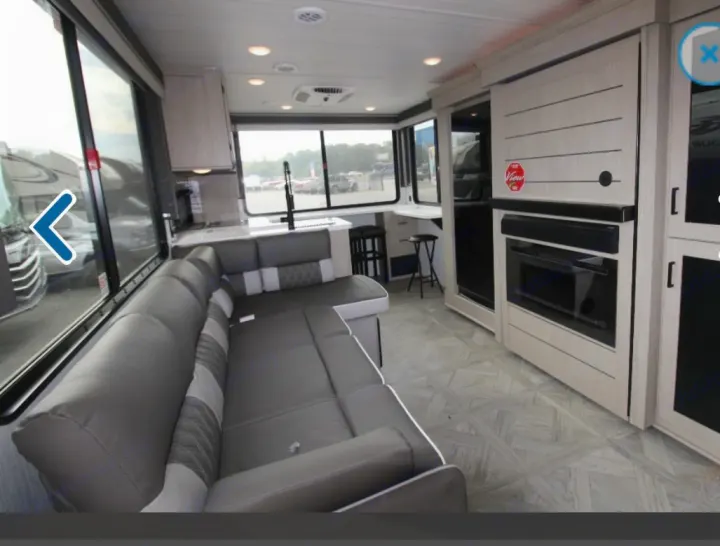 Inside a spacious rv rental: modern living area with L-shaped sofa, kitchen, and wide views from large windows.. Forest River Wildwood XLite View 2024