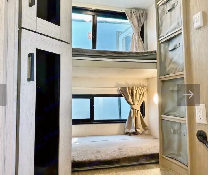 RV rental interior: A cozy bunk bed area with two bunks, windows with curtains, and convenient built-in storage.. Forest River Wildwood XLite View 2024