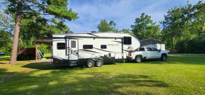 White pickup truck attached to a Reflection travel trailer RV, parked on a grassy area. Perfect for your next rv rental.. Grand Design Reflection 2021