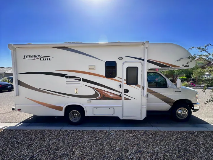 White Class C RV rental, a motorhome, parked on a bright sunny day. Ideal for your road trip adventure.. Thor Freedom Elite 2016