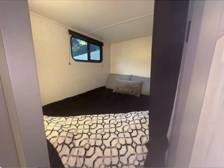 Cozy RV rental bedroom featuring a comfortable bed with a patterned blanket and window, perfect for travelers.. Heartland RVs North Trail 2023