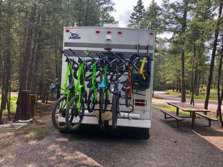 This RV rental is ready for adventure, featuring a loaded bike rack at a peaceful, tree-filled campsite.. Jayco Greyhawk 2010