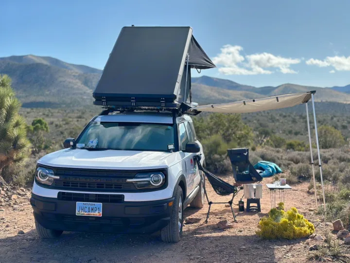 White SUV with a rooftop tent and side awning, set up for desert camping. An RV rental alternative for your overland adventure.. Ford Bronco Sport 2022
