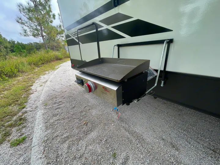 RV rental with an attached outdoor griddle for convenient camping meals on a gravel lot.. Dutchmen Kodiak Ultra Lite 2021