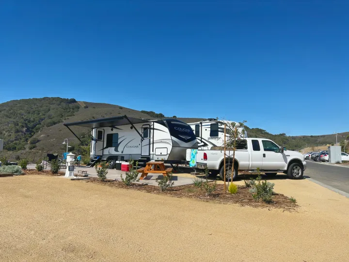 Enjoy your RV rental adventure! Fifth-wheel and truck at a sunny campsite with mountain views.. Keystone RV Cougar 2021