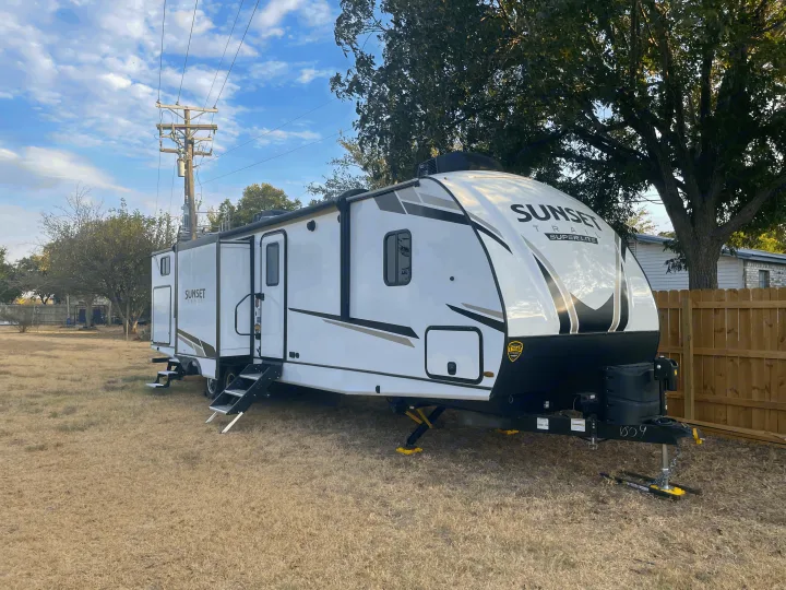 White Sunset Trail travel trailer RV rental parked outdoors with extended slide-out and steps.. Crossroads RV Sunset Trail 2022