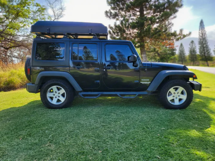 Side view of a black 4-door Jeep Wrangler with a rooftop tent, an ideal RV rental for camping & overland adventures.. Jeep Jeep Wrangler Overland 2017