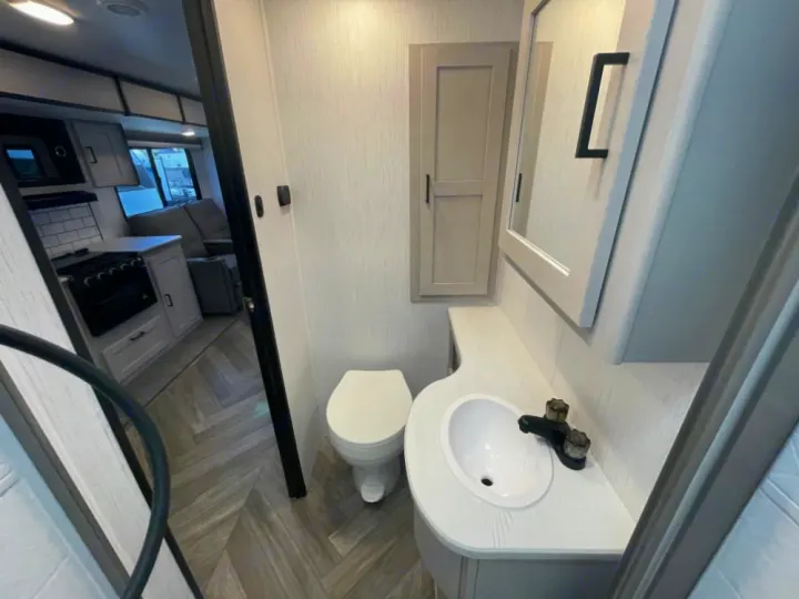 Explore this RV rental's modern interior featuring a bright bathroom with sink & toilet, and a compact kitchen area.. Heartland RVs Mallard 2023