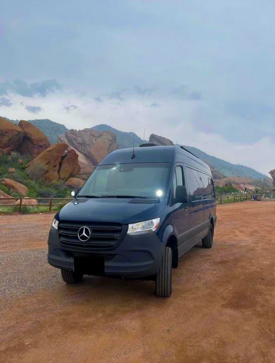 Dark Mercedes Sprinter RV rental van parked on dirt, with rugged mountains in the background.. Mercedes Sprinter Motorhome Campervan RV 2022
