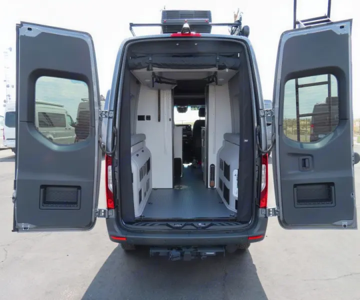 Dark gray RV rental camper van, rear view with open doors showing its spacious, customized interior with storage units.. Winnebago Revel 2024