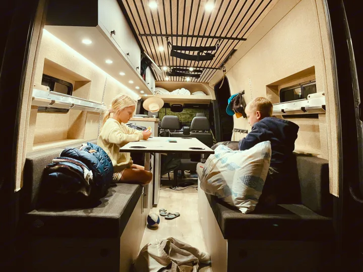 Kids enjoying card games in a cozy RV rental interior. Perfect for family adventures on the road.. Mercedes-Benz Sprinter 2020