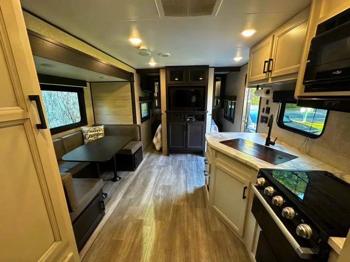 Modern RV rental interior with a spacious kitchen, built-in dinette, and entertainment center, offering comfort for travel.. Jayco Jay Flight SLX 2022