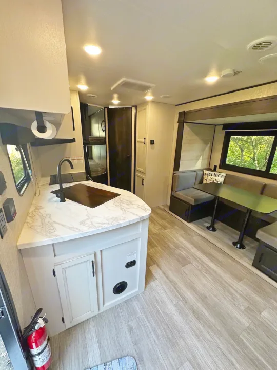 Modern RV rental interior with kitchen, dinette, and bunk beds. Features marble-look counters, wood-style floors, and natural light.. Jayco Jay Flight SLX 2022
