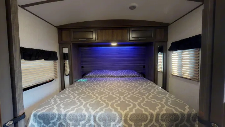 Cozy RV rental bedroom with a comfy bed, overhead storage, and ambient lighting. Perfect for travel trailer trips.. Crossroads RV Sunset Trail Super Lite 2021
