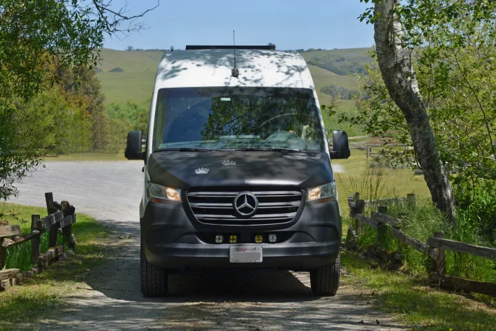 Camper van RV rental on a gravel road, surrounded by trees & hills. Perfect for exploring nature.. Mercedes-Benz Sprinter 2021