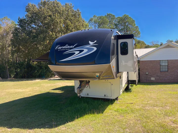View of a large Cardinal fifth-wheel RV on a sunny day. Ideal for an RV rental vacation, parked beside a home.. Forest River Cardinal 2015