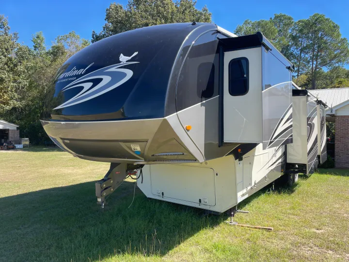 A large, modern Cardinal fifth-wheel RV rental, featuring extended slide-outs, parked on a sunny day on green grass.. Forest River Cardinal 2015