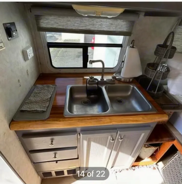 Efficient RV rental kitchen features a double sink, wood countertop, gray cabinets, and window, optimizing space.. Ford Econoline 2004