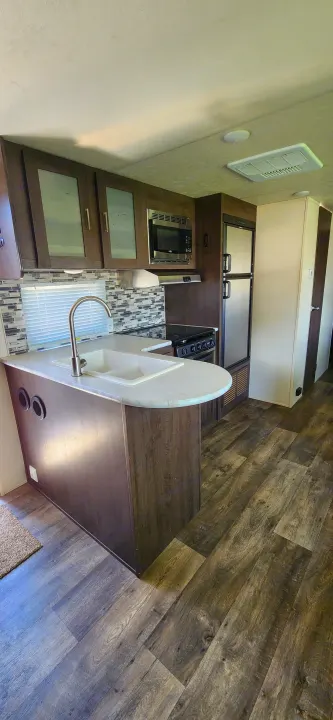 Well-appointed RV rental interior showcasing a full kitchen with modern appliances and wood-look flooring.. Forest River Salem Cruise Lite 2018