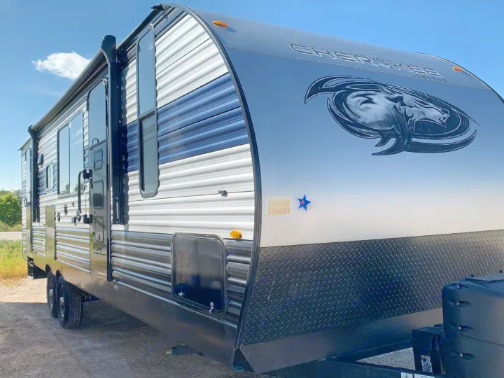Get ready for adventure with this grey and blue Cherokee travel trailer rv rental, featuring a distinctive wolf logo and front diamond plate.. Forest River Cherokee 2022