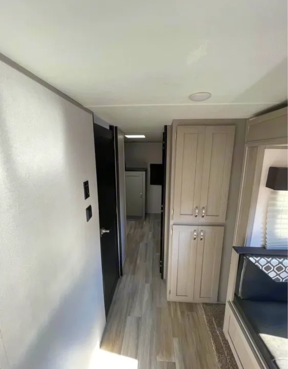 Spacious RV rental interior with a hallway, modern cabinets, and wood-look flooring.. Forest River Tracer 2021