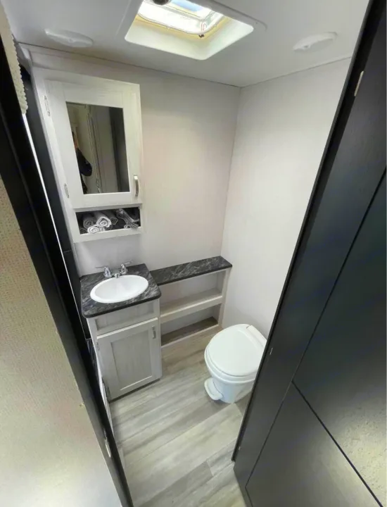 A well-appointed compact bathroom in an RV rental, featuring a sink, toilet, and ample storage space.. Forest River Tracer 2021