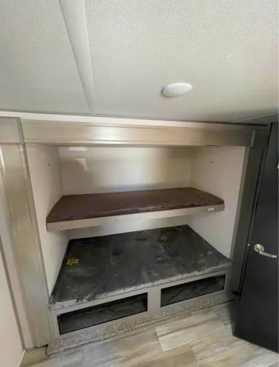 RV rental interior: two stacked bunk beds with mattresses and bottom storage, ideal for travel trailer trips.. Forest River Tracer 2021