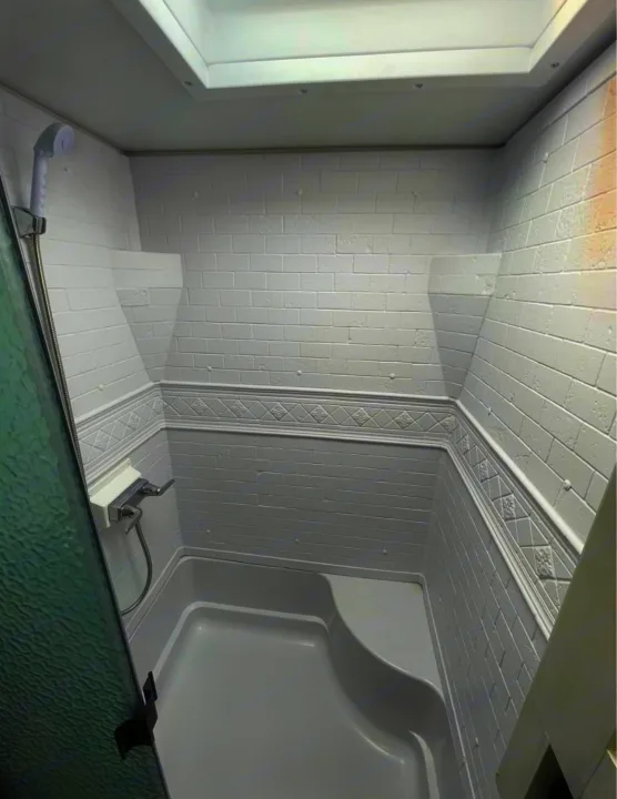 Clean, compact RV rental shower with white brick-patterned walls, molded seat, and skylight. Perfect for your travels.. Forest River Tracer 2021
