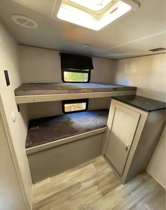 RV rental bunk beds offer comfortable sleeping for two, with windows and a convenient storage cabinet.. Forest River Tracer 2021