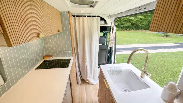 Step into this chic RV rental! Features a compact kitchen with a sink, cooktop, wood cabinets, & outdoor views.. Mercedes-Benz Sprinter 2020