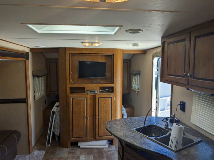 Spacious RV rental interior featuring a kitchen with sink, TV area, and access to a bedroom in this camper.. Crossroads RV Z-1 2016