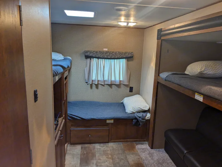 This RV rental interior features a bunkhouse with three beds (two bunks on left), a window, and built-in storage.. Crossroads RV Z-1 2016